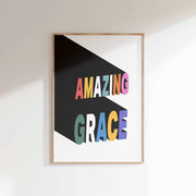 Poster featuring the text 'AMAZING GRACE' in colorful letters on a black background, framed in wood.