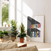 Colorful 'AMAZING GRACE' poster displayed in a bright room with plants and natural light, modern wall art.