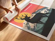 A person unrolling a poster featuring a silhouette of a deer against a sunset and mountains, with the text Habakkuk 3:19.