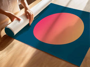 A person rolling up a colorful poster featuring a large gradient circle on a dark background, with sunlight casting shadows.