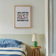 Poster with the text 'I WILL GIVE YOU REST' and 'MATTHEW 11:28' in colorful letters, framed and displayed on a wall.