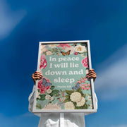Poster featuring floral design and text 'In peace I will lie down in sleep. Psalm 4:8' against a blue sky.