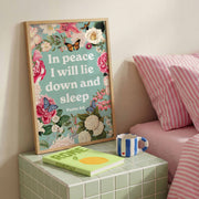 Framed poster with floral design and text 'In peace I will lie down and sleep. Psalm 4:8' on a bedside table.