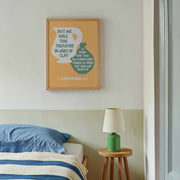 Framed poster with the text 'We Have This Treasure In Jars of Clay - 2 Corinthians 4:7' on a wall, modern decor.