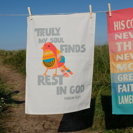 Decorative towels with bible quote hanging on a clothesline outdoors.