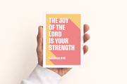 Postcard featuring the text 'The Joy of the Lord is your strength' with Nehemiah 8:10, held in a hand.