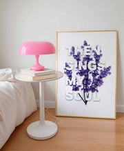 Poster featuring the text 'THEN SINGS MY SOUL' with purple flowers, displayed beside a pink lamp and a stack of books.