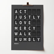 Act justly, love mercy, walk humbly — Micah 6:8 poster in white flip-board lettering on charcoal grey, held by a bulldog clip.