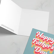 Greeting card with colorful text saying 'Happy Father's Day' on a light blue background, inside is blank.