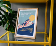 Framed poster featuring mountains and a blue sky with text from Psalm 121, displayed on a yellow shelf.