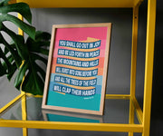 Framed poster featuring colorful text of Isaiah 55:12, displayed on a yellow shelf with a green plant.