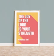 Poster featuring the text 'The joy of the Lord is your strength' in bold white letters on a pink and yellow background, with