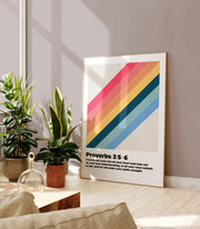 Wall art poster featuring Proverbs 3:5-6 with colorful diagonal stripes, displayed in a bright room with plants.