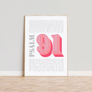 Modern typographic poster featuring Psalm 91 in pink and gray, framed against a light wall.