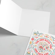 Greeting card featuring the text 'The Lord Bless You and Keep You' with floral designs and a bible verse.