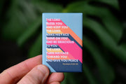 Magnet featuring a colorful design with the text of Numbers 6:24-26, held against a green background.