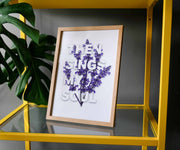 Framed poster with the text 'Then sings my soul' in white, adorned with purple flowers, displayed on a yellow shelf.