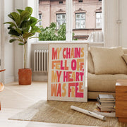 Poster with the text 'My chains fell off, my heart was free' in pink and yellow, displayed in a cozy living room.