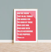Coral poster featuring Romans 8:28 text in white, framed against a light gray wall, minimalist design.